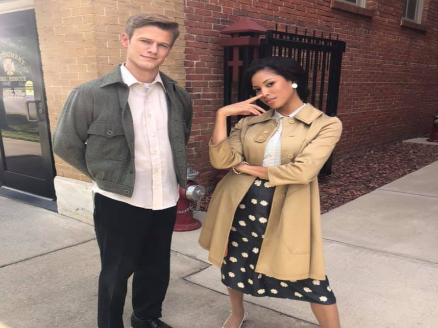Man and woman posing outside brick building.