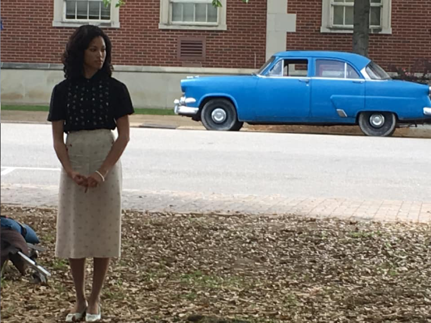 Woman standing near a vintage blue car.