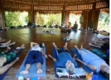 People practicing yoga in a wooden pavilion.