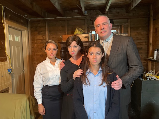 Four people posing in a wooden room.
