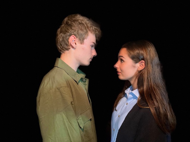 Two people facing each other in darkness.