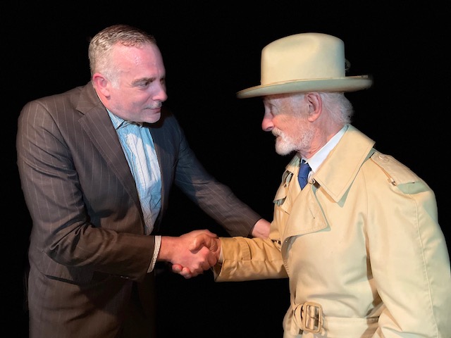 Two men shaking hands, wearing suits.